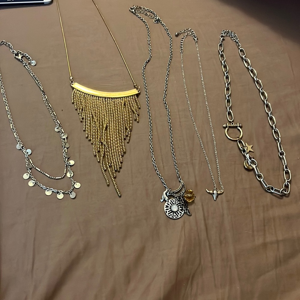 One gold and four silver necklaces all with accented beads